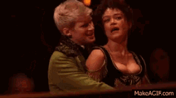 a man and a woman are standing next to each other on a stage and looking at each other .