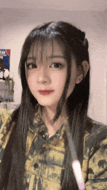 a girl with long black hair is wearing a yellow shirt