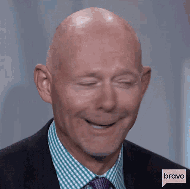 a bald man wearing a suit and tie is smiling with bravo written on the bottom