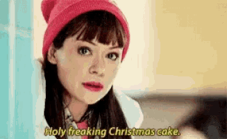 a woman wearing a red hat and a white coat is talking about christmas cake .