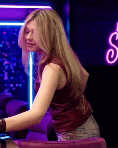 a woman sitting in front of a neon sign that says s.