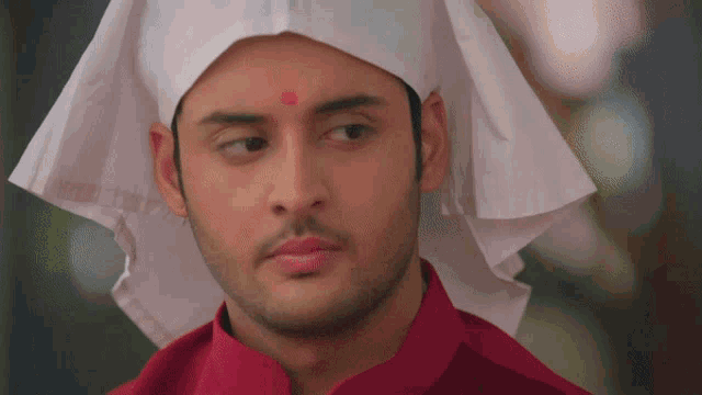 a man wearing a red shirt and a white hat looks at the camera