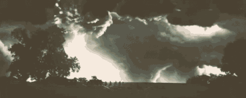 a black and white photo of a storm with trees in the foreground .