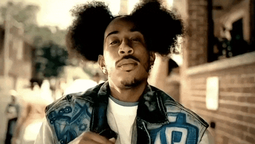a man with curly hair and a beard is wearing a denim vest with the letter r on it .