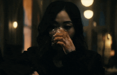 a woman is drinking from a glass in a dark room .