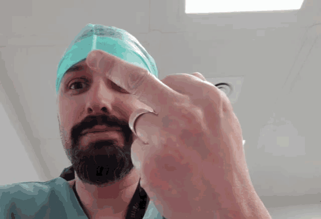 a man with a beard is wearing a surgical cap and a ring