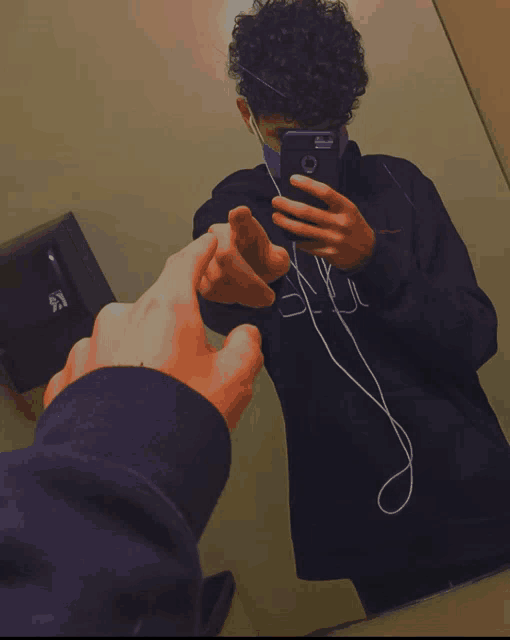 a person taking a picture of another person in front of a paper dispenser that says k on it