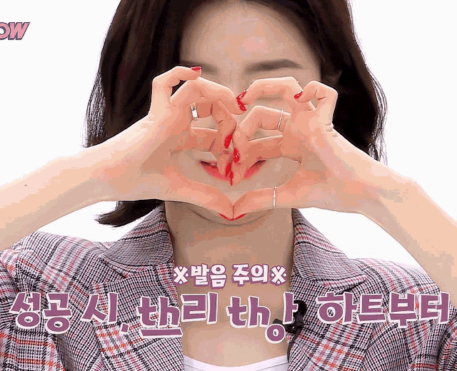a woman making a heart shape with her hands in front of her face with chinese writing behind her