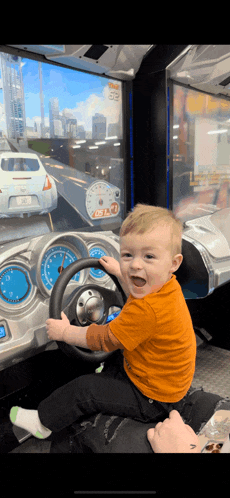 a baby is playing a video game with a steering wheel