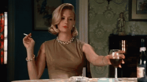a woman is smoking a cigarette and drinking a glass of wine