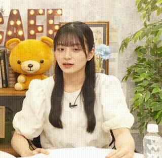 a girl in a white shirt is sitting at a table with a teddy bear .