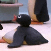 a stuffed penguin is sitting on top of another stuffed penguin on the floor .