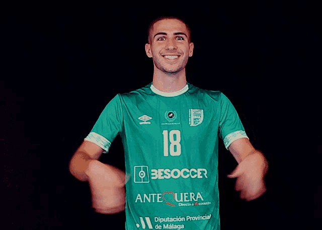 a man wearing a green besoccer shirt is smiling