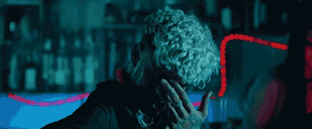 a man with curly hair has his hand on his face