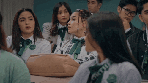 a group of students are sitting in a classroom with one girl wearing a lanyard that says ' oru ' on the front