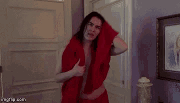 a woman wrapped in a red blanket is standing in a room .