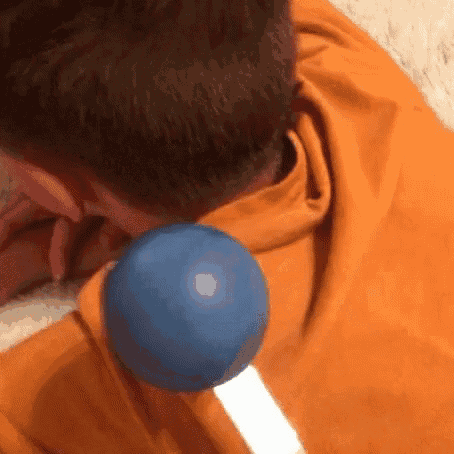 a person is laying on a bed with a blue ball on their back .