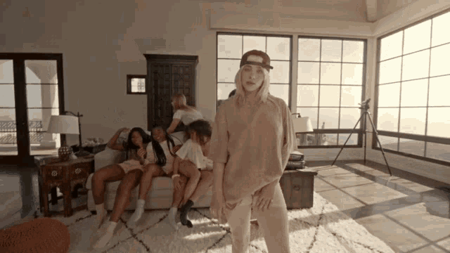 a group of women are sitting on a couch in a living room with a woman standing in front of them