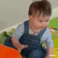 a baby in overalls is sitting on a table with toys .