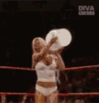 a woman in a wrestling ring is pouring water on another woman .