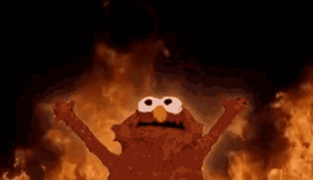 elmo from sesame street is standing in front of a fire with his arms in the air .