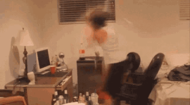 a blurry picture of a person standing in a room with a computer and chair