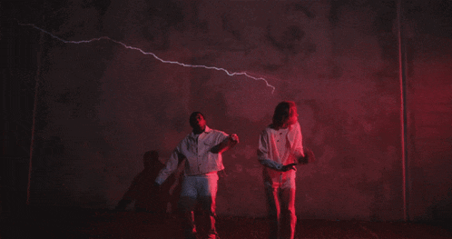 a man and a woman are dancing in front of a white wall