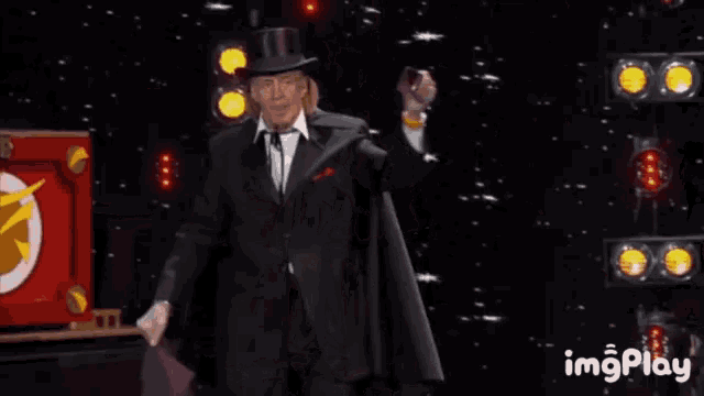 a man in a top hat stands in front of a box that says imgplay on the bottom