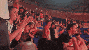 a crowd of people applauding in a stadium with a man wearing a red shirt that says ' nba '