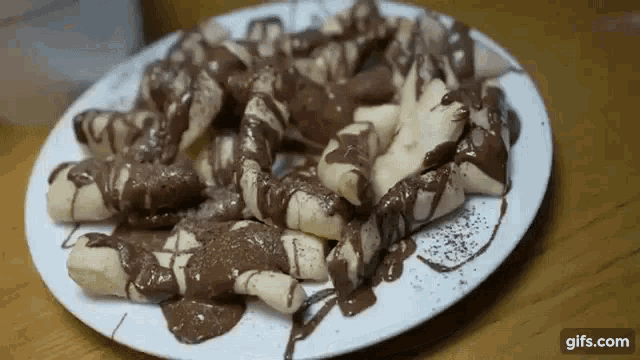 a white plate topped with bananas covered in chocolate sauce ..