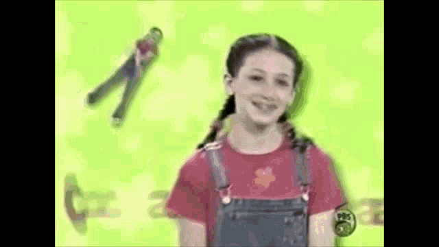 a girl in overalls is standing in front of a green background with a man flying in the background .