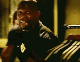 a man in a black shirt with a gold badge on his chest is smiling