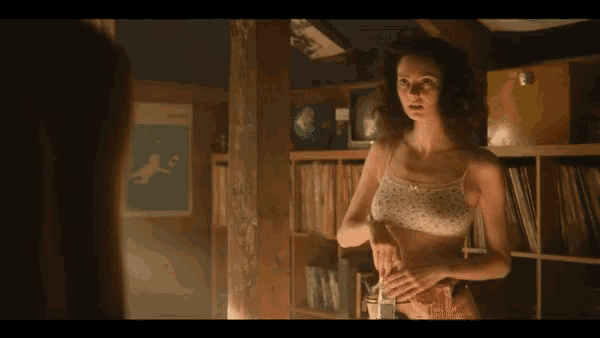 a woman in a bra is standing in front of a shelf with records on it