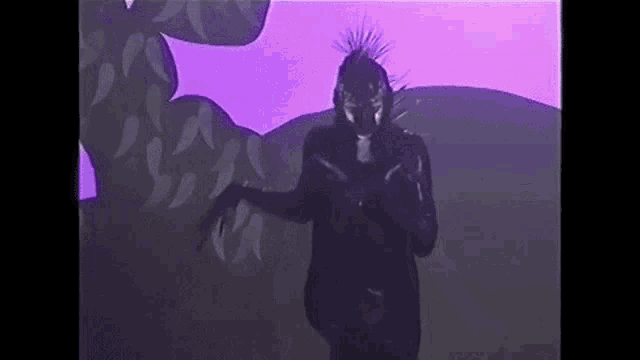 a person in a black costume is standing in front of a purple background .