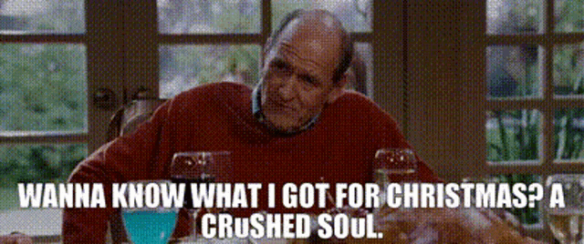 a man in a red sweater is sitting at a table with a crushed soul cocktail .