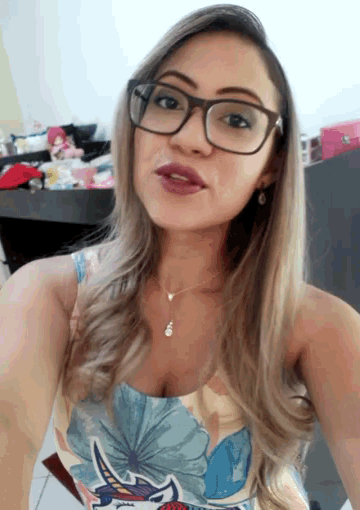 a woman wearing glasses is taking a selfie in front of a desk