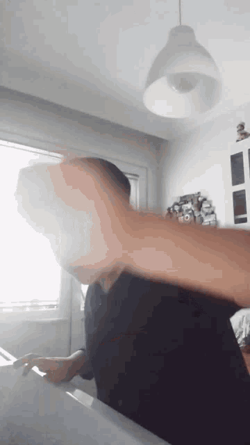 a man is standing in front of a window with his fist up