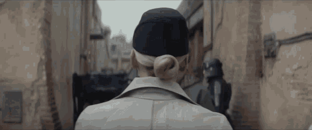 a woman in a trench coat and hat is walking down a street