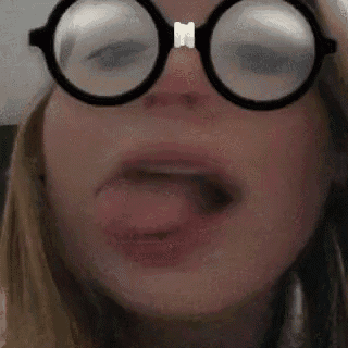 a close up of a woman wearing glasses with her tongue sticking out .