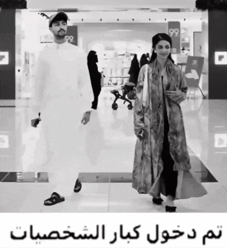 a black and white photo of a man and a woman walking in a store