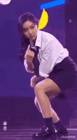 a woman in a white shirt and tie is squatting down and making a middle finger gesture .
