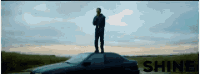 a man standing on top of a car with the word shine in the background