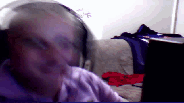 a person wearing headphones is sitting on a couch in front of a laptop computer