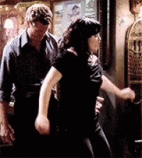 a man and a woman are standing next to each other in a room . the woman is holding the man 's arm .