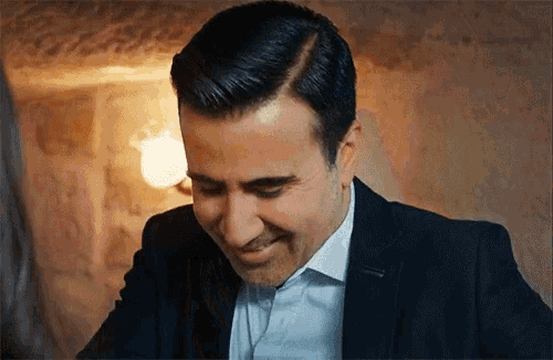 a man in a suit and white shirt is smiling with his mouth open .