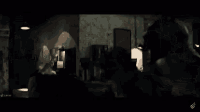 a man in a batman costume is standing in a dark room with a clock on the wall .