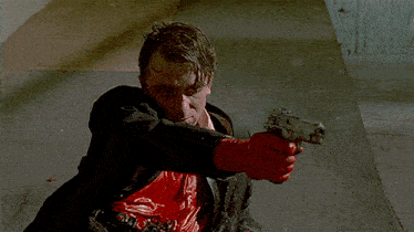 a man in a suit and red tie is holding a gun