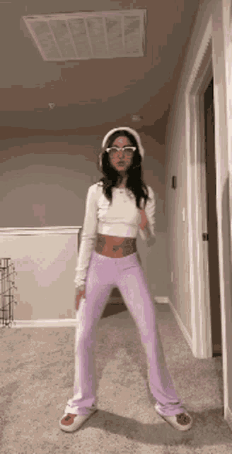 a woman in purple pants and a white hat is dancing in a hallway .