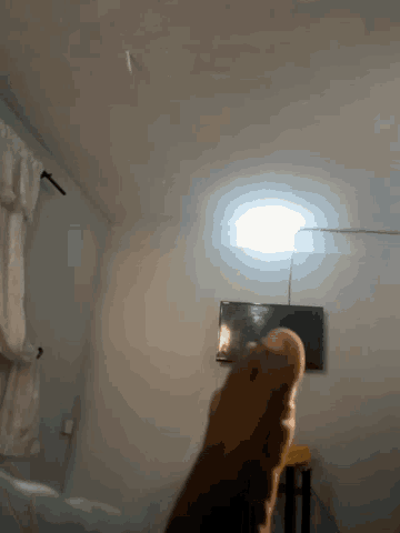 a person 's hand is reaching out towards a light in a room