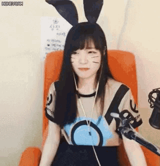 a girl wearing bunny ears is sitting in an orange chair